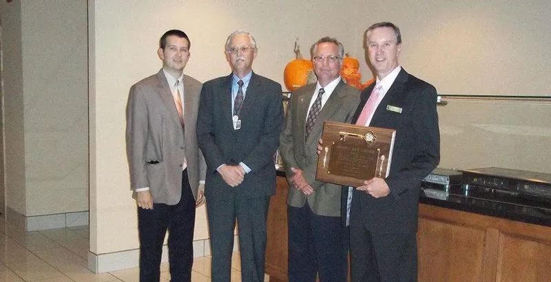Four men in suits holding a plaque at Marriott 20 & Oaks
