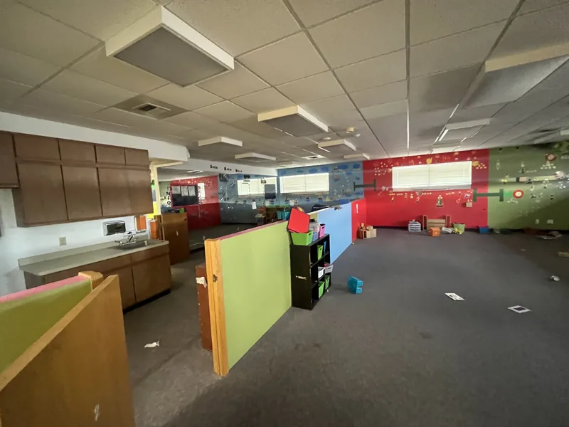 Daycare interior before renovation, with old carpet and colorful partitions