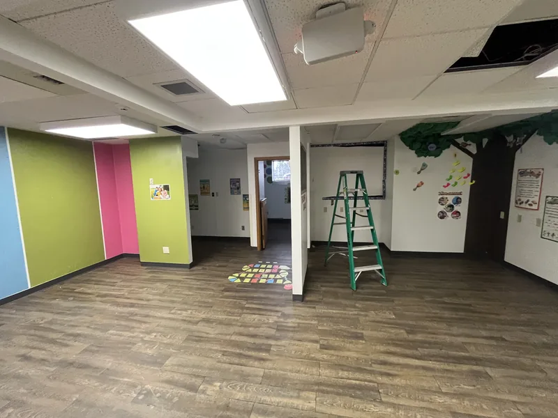 Daycare interior before renovation, with painted walls and a ladder
