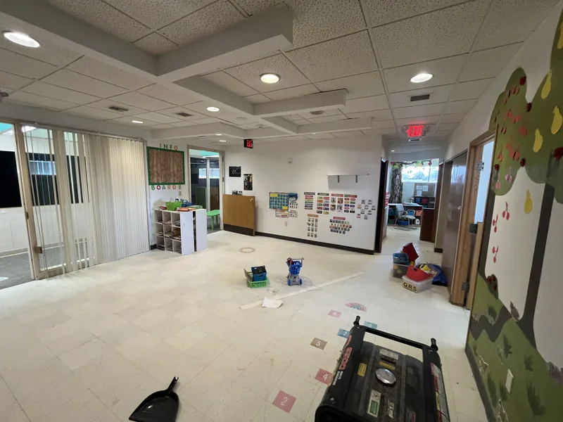 Daycare room before renovation, with mural walls and toys